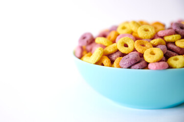 Closeup shot of multicolored fruity cereals in a blue bowl isolated on white background