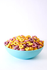 Vertical shot of multicolored fruity cereals in a blue bowl isolated on white background