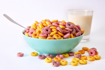Closeup shot of multicolored fruity cereals and glass milk isolated on a white background

