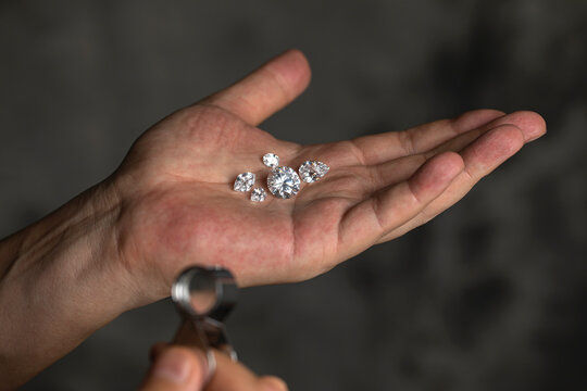 Large polished round cut diamond in hand close up front view. High quality photo