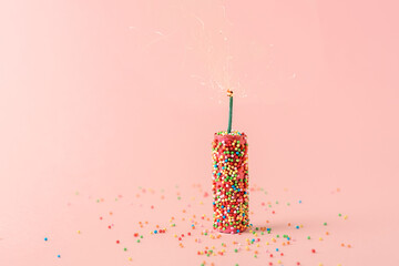 Creative concept of the holiday. Pink firecrackers with sweet balloons on a pink background.