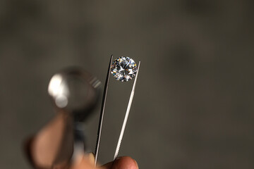 Large polished round cut diamond in hand close up front view. High quality photo