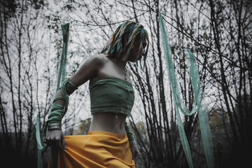 dead girl in autumn foliage wearing green and yellow robes