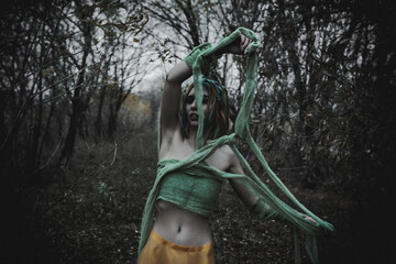 dead girl in autumn foliage wearing green and yellow robes