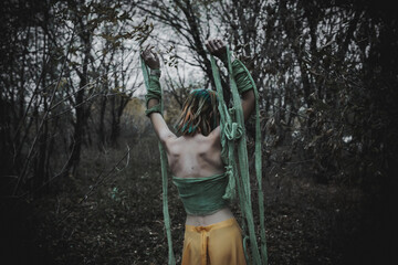 dead girl in autumn foliage wearing green and yellow robes