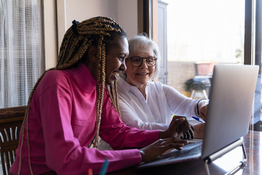 Young African woman teaching computer skills to an older woman