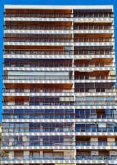 Fototapeta na wymiar Spain; Dec 2020: Facade of an apartments building with balconies, the building looks like a hive, vertical composition with straight lines. Interlimen, Hondarribia, Basque country, Spain