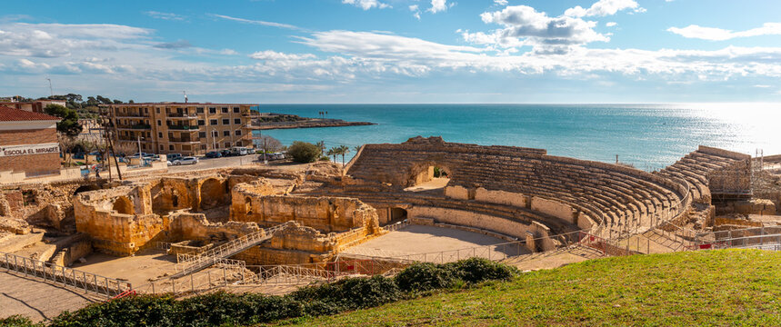 Ruins of ancient Roman amphitheater built during the Roman empire, Romanesque church inside, city of Tarraco - Tarragona, Catalonia, Spain, by the Mediterranean sea. Full view panoramic picture