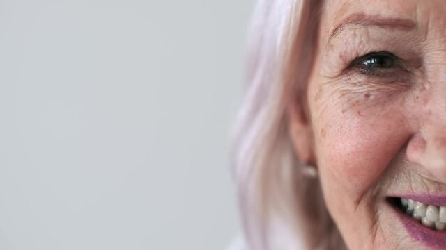 Skin Care, Senior Woman, Home Cosmetics, Elderly Age, Cosmetic Procedures. Close-up, half of the face. Elderly woman 70 years old with wrinkles on her face looking at the camera and smiling