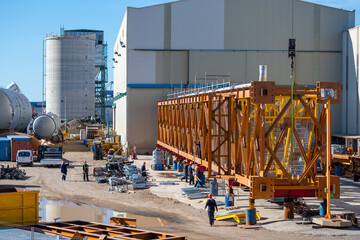 Spain; Jan 2021: Heavy large iron beam to be used for a construction of a bridge, workers at a construction site preparing the beam for its transportation, in an industrial harbor in Tarragona, Spain