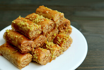 Plate of Crispy and Sweet Baklava Pastries with Pistachio Nuts on Black Wooden Background