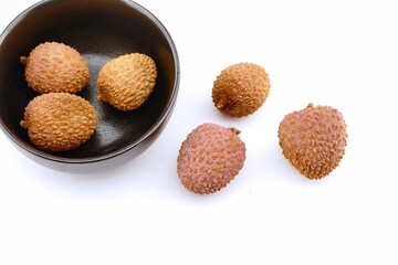 lychee fruits inside a black bowl grouped on white background, isolated, close up photo