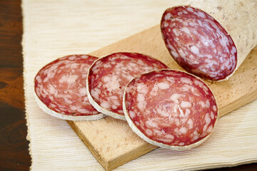 homemade salami sliced on wooden cutting board. typical handmade dish. pork sausages. close up