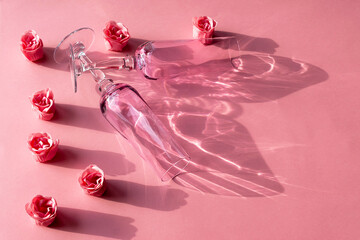 Valentine's day table setting. Two glasses and artificial roses on a pink background.