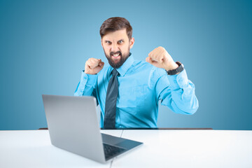 a businessman in a blue shirt clenches his fists and aggressively shows readiness to attack, a man with a beard behind a laptop is set to attack