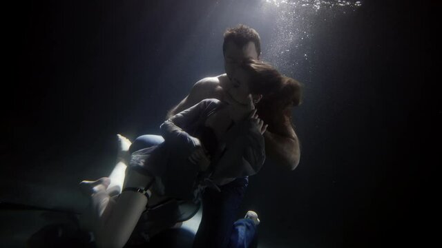 foreplay underwater, man is hugging his girlfriend dressed erotic lingerie and silk gown, floating in depth
