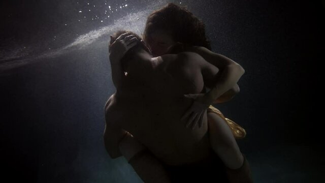 young man and woman are having sex underwater, medium shot of muscular naked male back, slow motion subaquatic view