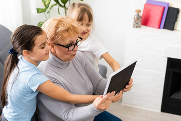 Grandmother with young girl use touch screen tablet computer smiling