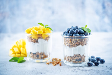 Mango  and blueberry Greek yogurt granola parfait in a glass