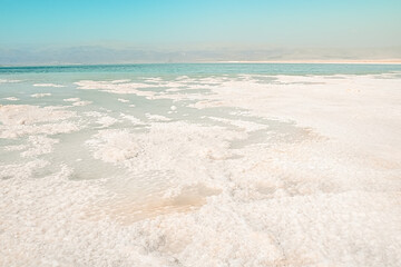 Fototapeta na wymiar texture of salt deposits bank on the Dead Sea, Israel, beautiful landscape on a clear day with clear blue sky, jordan mountains view. Flakes of salt under the water.