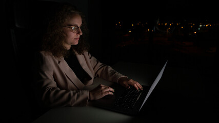 Woman in suit working at night. Concept of overwork in the office.
