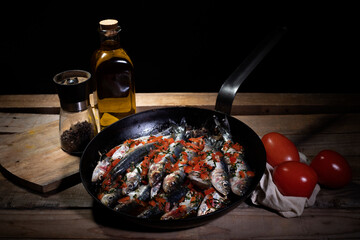 still life  of frying pan with fish, tomatoes and olive oil