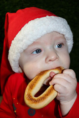 christmas gift - cute smiling child in red santa hat in the cardboard box eating the bagel close up portrait