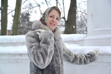 Portrait of young woman in fur coat and headscarf in winter park
