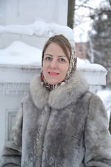 Portrait of a young woman in a fur coat on the background of a building