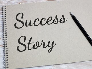 Phrase Success Story written on note book with pen. Business concept.