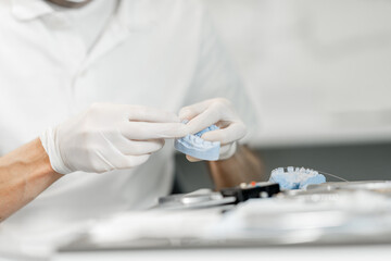 Dental technician working with a model of teeth trying on a brace system for orthodontic treatment...