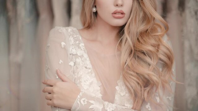 Sensual woman in wedding dress in bridal salon. Portrait of sensitive model touch her body in gown