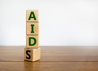 Symbol for helping people with aids, Acquired immunodeficiency syndrome. Turned a wooden cube with words aids aid. Beautiful white background, copy space. Medical and aids aid concept.