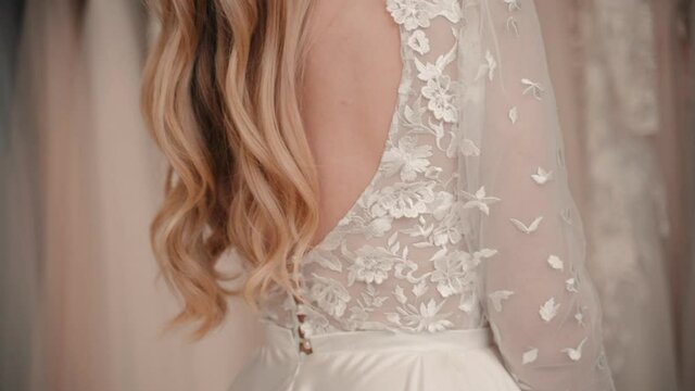 Closeup of woman fitting wedding dress in salon. Hand touch shoulder. Sensual gesture. Bride choose
