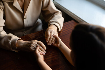 Obraz premium Young granddaughter taking care of grandmother with tender and care. Wrinkled hands of very old woman and young hands of teen woman close up, the change of family generation. Healthcare and wellness.