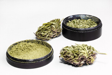 grinder full of dry herb and joint with medical marijuana with paper filter and piece of rolling paper on white background