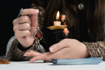 Fortune teller with a magic pendulum in the hands close up concept.