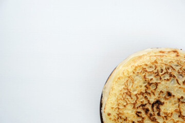 Pancake Week butter festival lunch. A stack of Russian pancakes on a light rustic wooden background. Top view with copy space. 