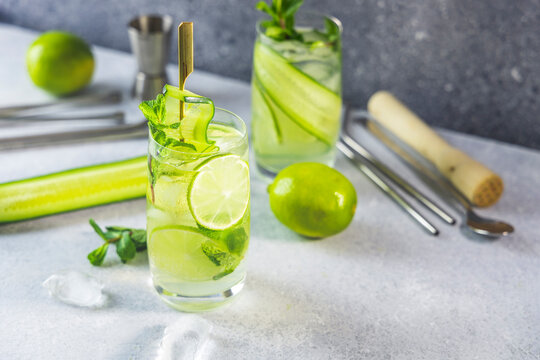 Detox cocktail with mint, cucumber and lime or mojito cocktail in highball glasses on a gray concrete stone surface background.