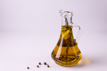 Bottle with olive oil and basil branch against white background.