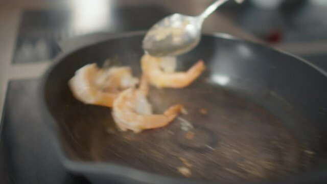 Slowmo close up of unrecognizable chef cooking tiger prawns in pan on induction cooker at restaurant kitchen