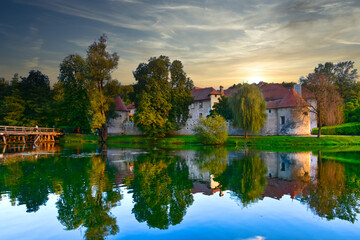 Obraz premium Castle Otočec on the river Krka in southern Slovenia, evening sunset scene with reflection of castle on the water