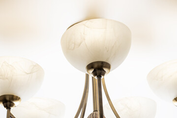 abstract light equipment concept. bronze chandelier lamp with marble glass over white ceiling background