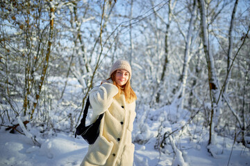 Fototapeta na wymiar Young woman walks on the background of a snowy forest