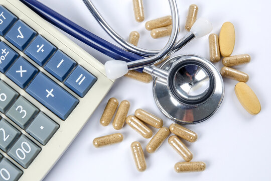Close-up Of Pills With Stethoscope And Calculator On Table