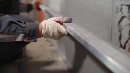 Plasterer at work on construction site, leveling walls and checking quality. Industrial worker on...