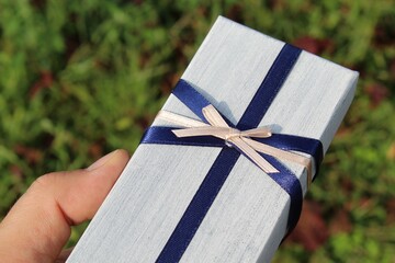 Regalo con fiocchetto blu e rosa nelle mani di un uomo