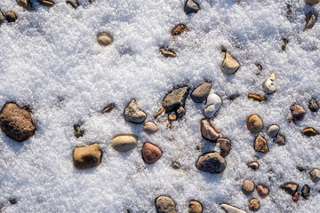 Latvia Baltic Sea beach in winter when snow has fallen on the sand and only stones are visible that form an interesting pattern