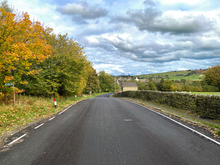 Looking along, Marsh Lane in autumn, with old trees, dry stone walls, and a cloudy sky in, Oxenhope, Keighley, UK
