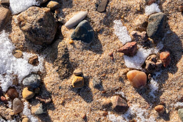 Latvia Baltic Sea beach in winter when a little snow has fallen on the sand then the stones form an interesting pattern